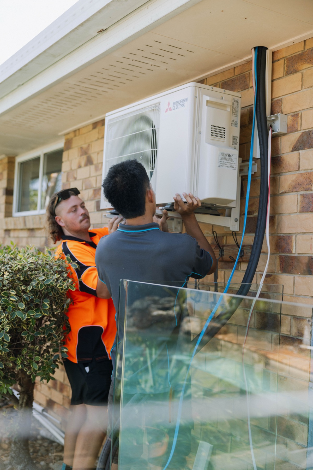 Parker Air technician completing final connections on a Mitsubishi Electric outdoor unit at a residential install