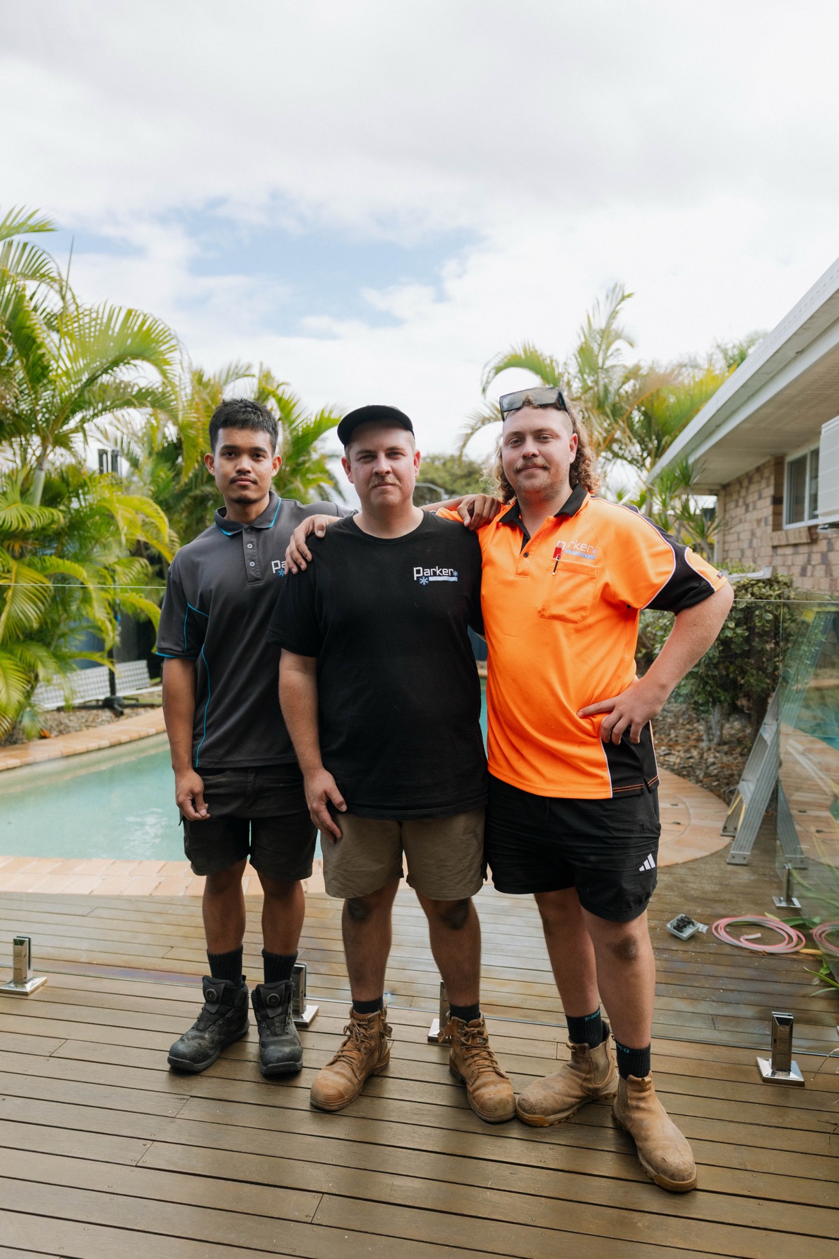 Parker Air Solutions team standing poolside after completed installation in Brisbane Northside