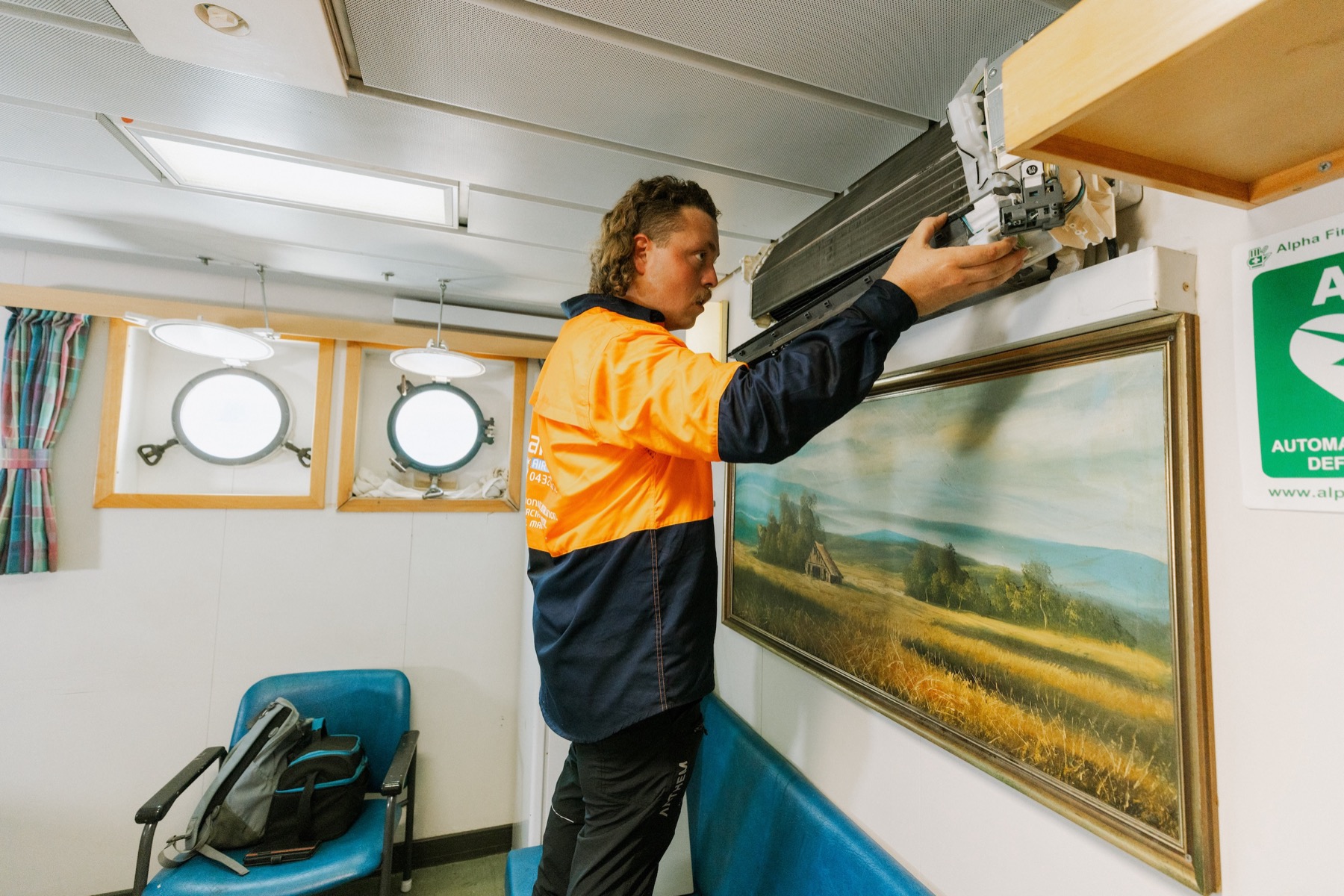Technician performing marine AC maintenance in vessel cabin