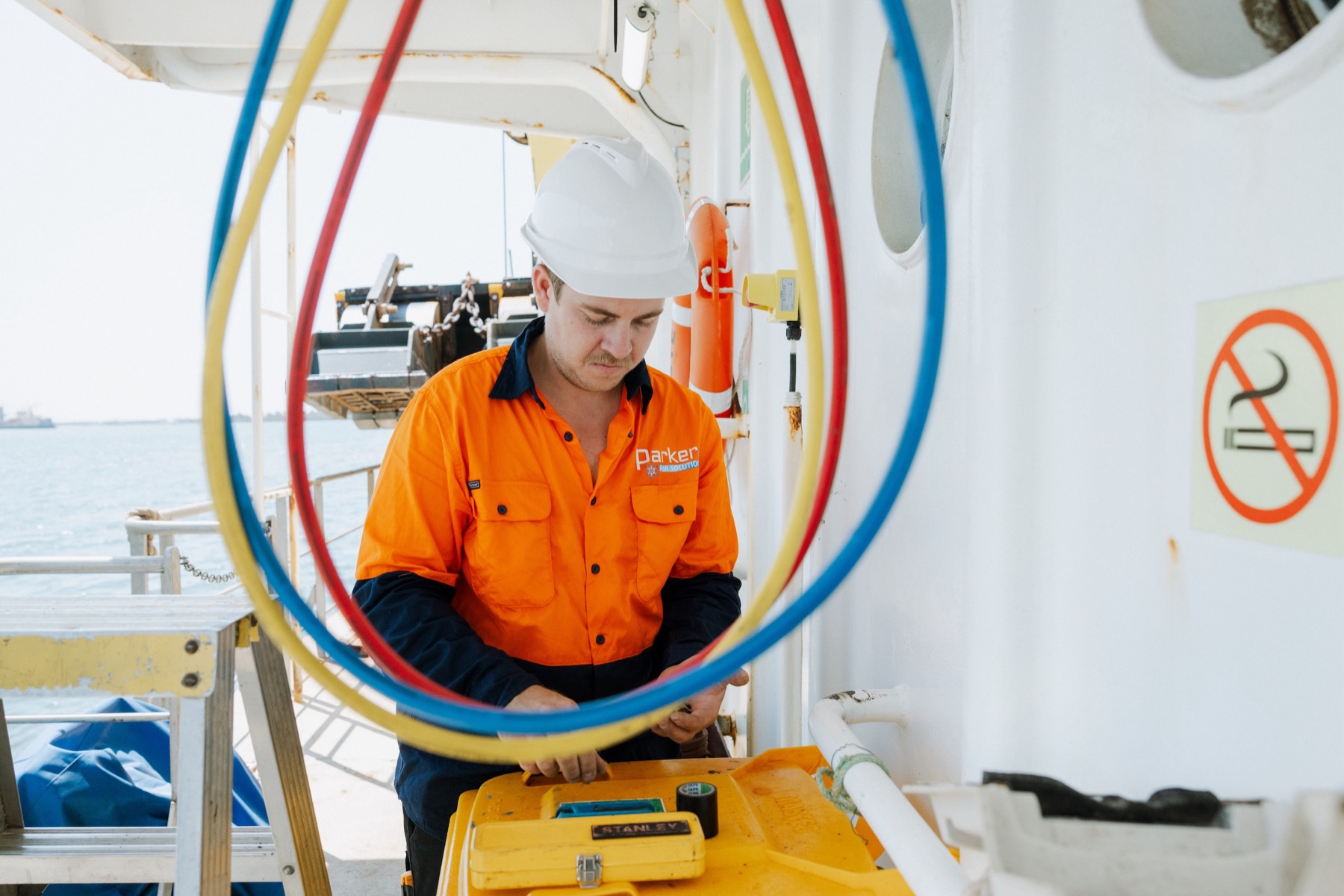 Marine AC technician working with refrigerant hoses on vessel