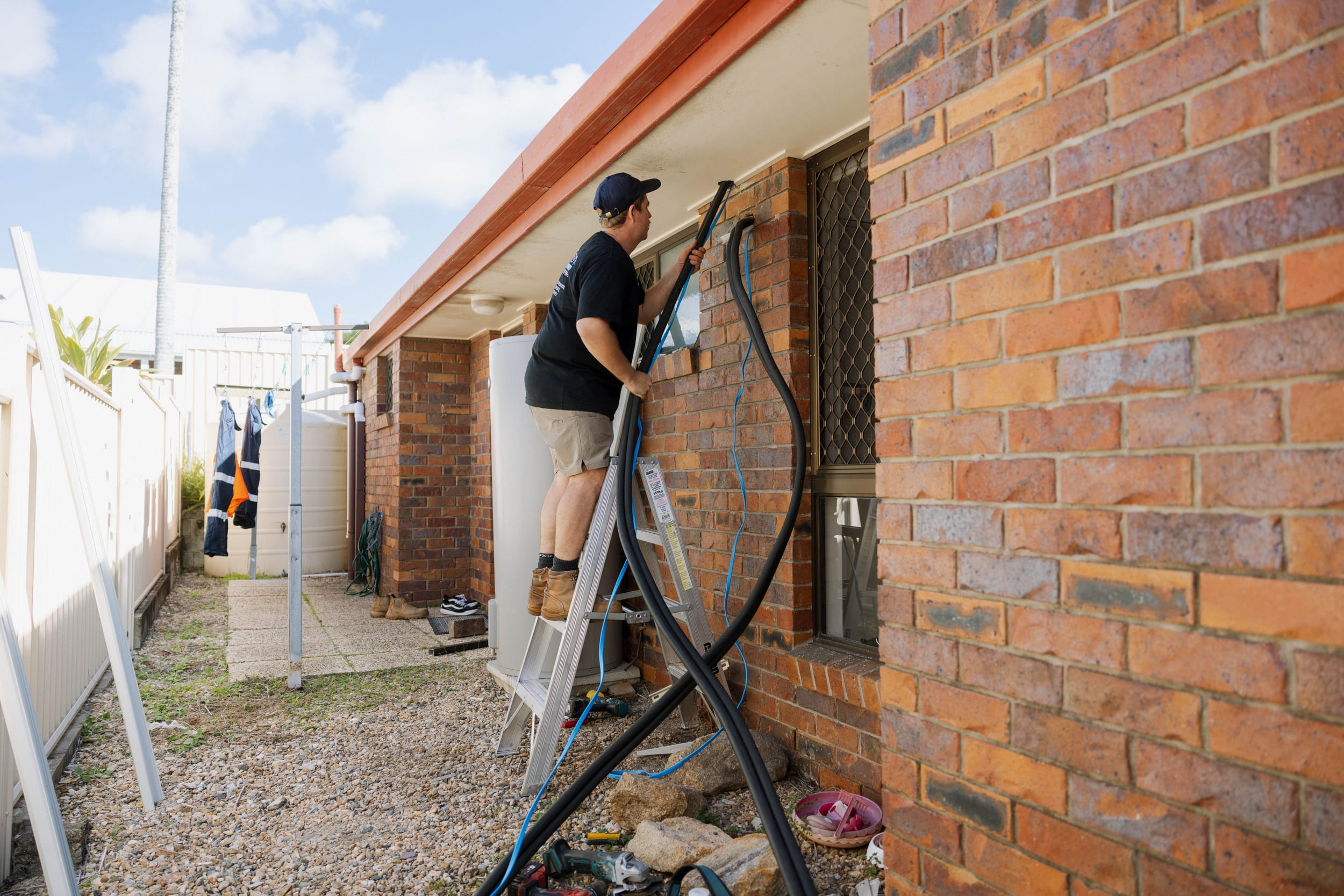 Side-exit refrigerant pipework run cleanly down the brick wall of a McDowall home