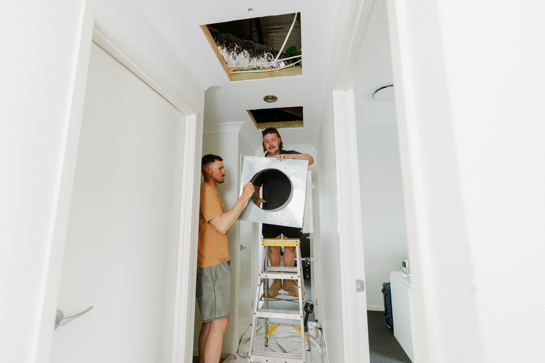 Parker Air Solutions team installing a ducted air conditioning unit into a ceiling space