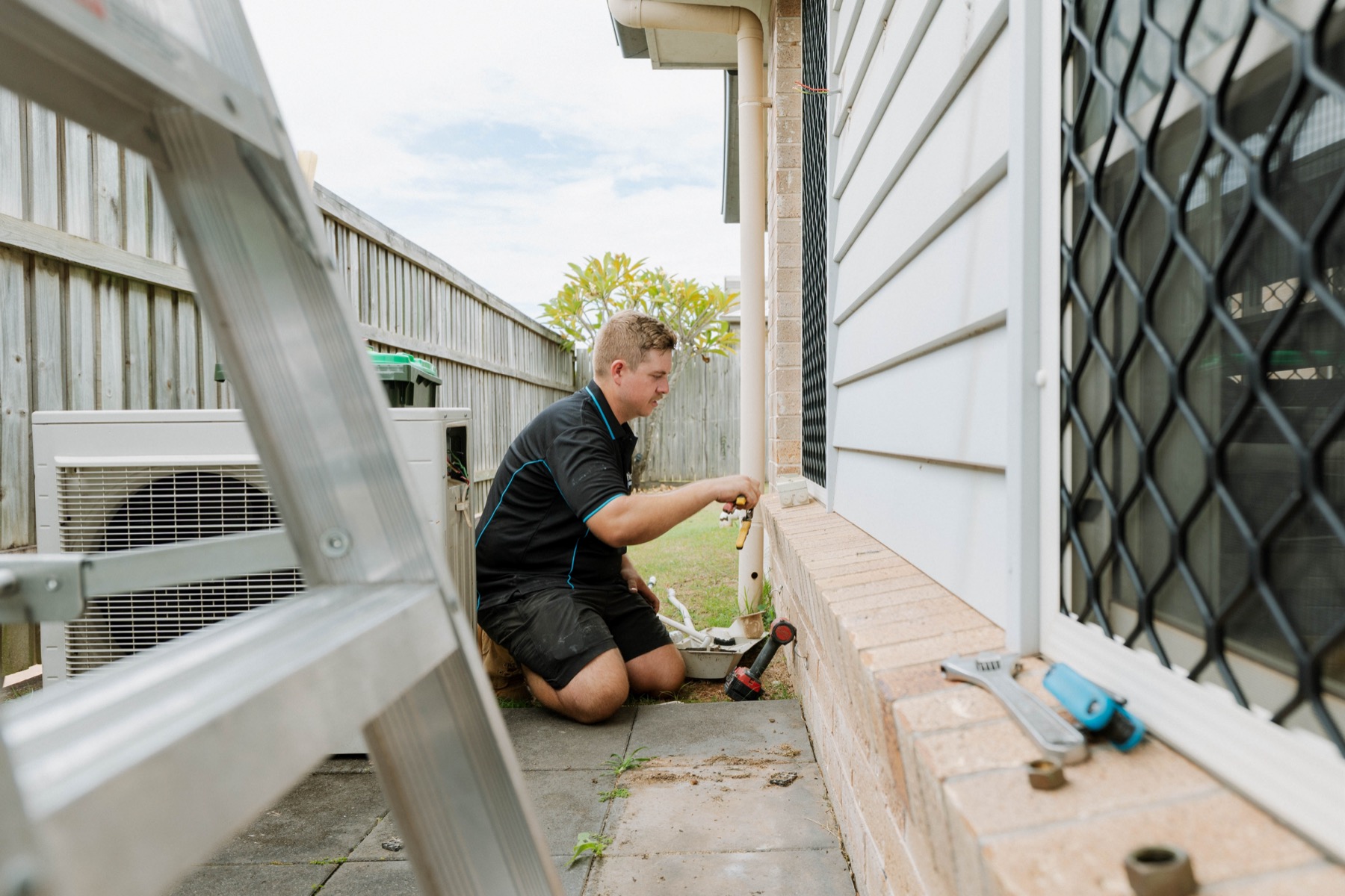 Technician connecting outdoor unit pipework for ducted air conditioning in Kallangur